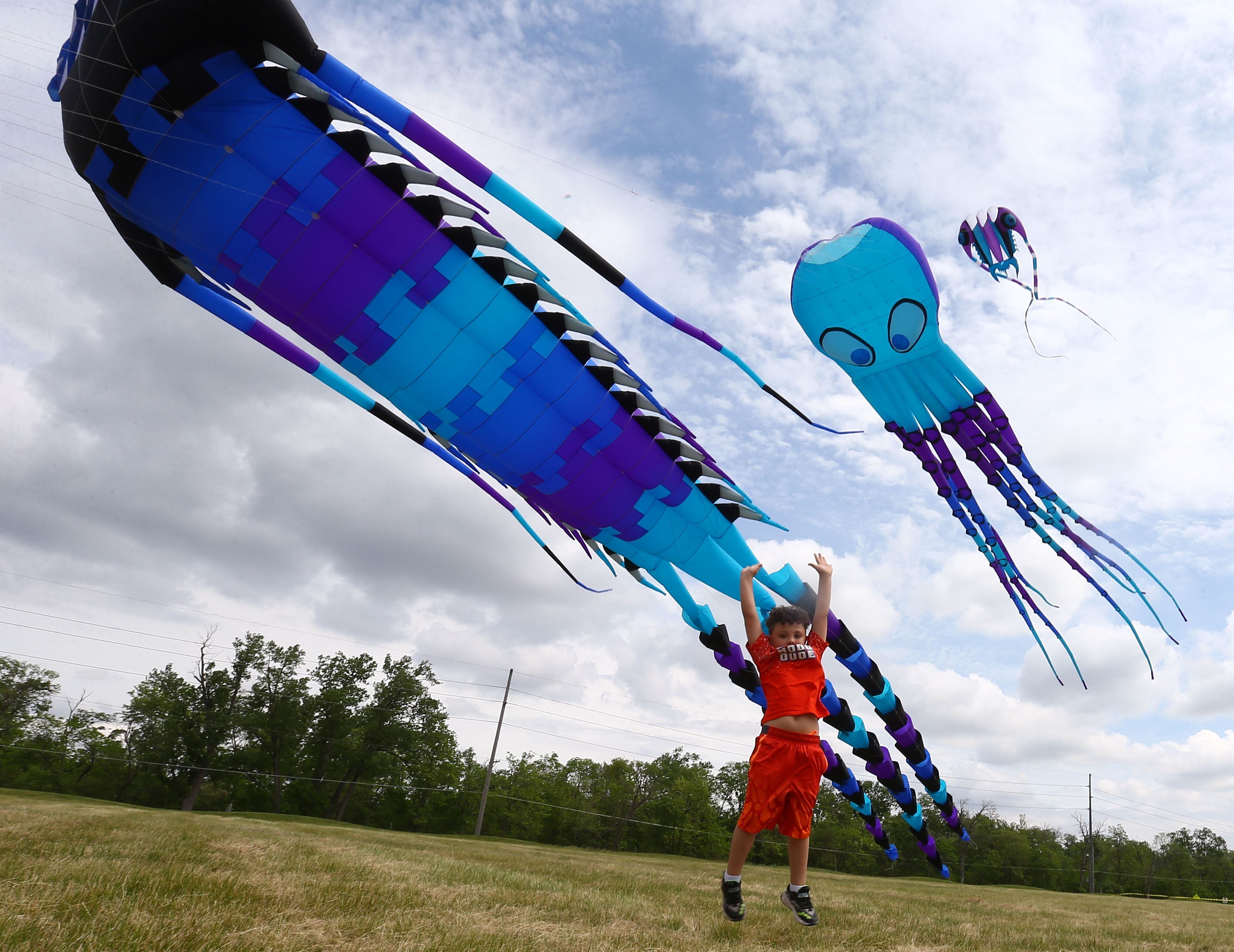 Dominick Anderson, jumps in the air to try to reach the giant kites flying in the air at the "Kites in Flight" event at Heritage Harbor in Ottawa, on Sunday May 23, 2021.