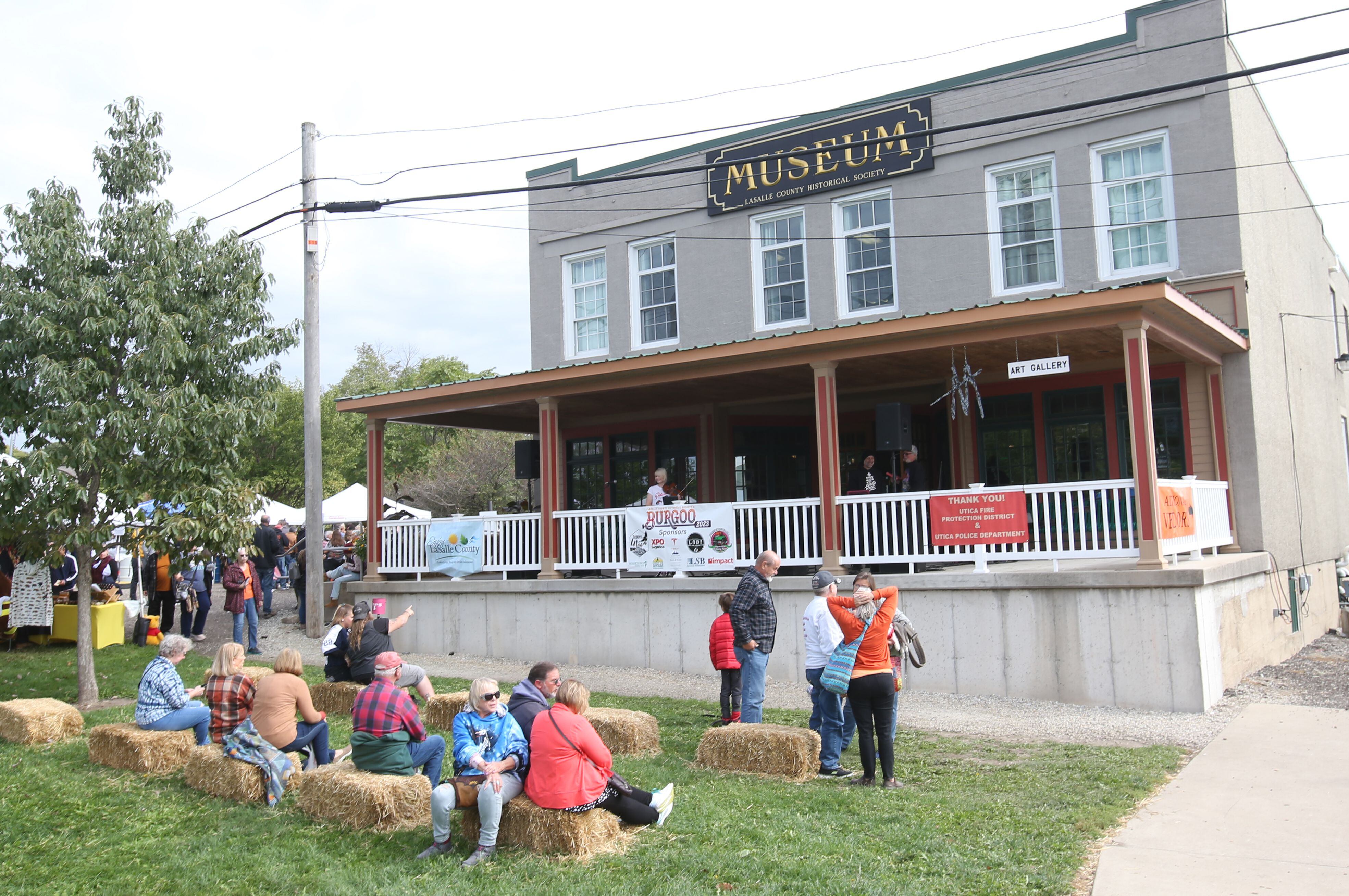 People watch violinish Casey McGrath play music on the front porch of the La Salle County Historical Society Canal Market building during the 53rd annual Burgoo on Sunday, Oct. 8, 2023 downtown Utica.