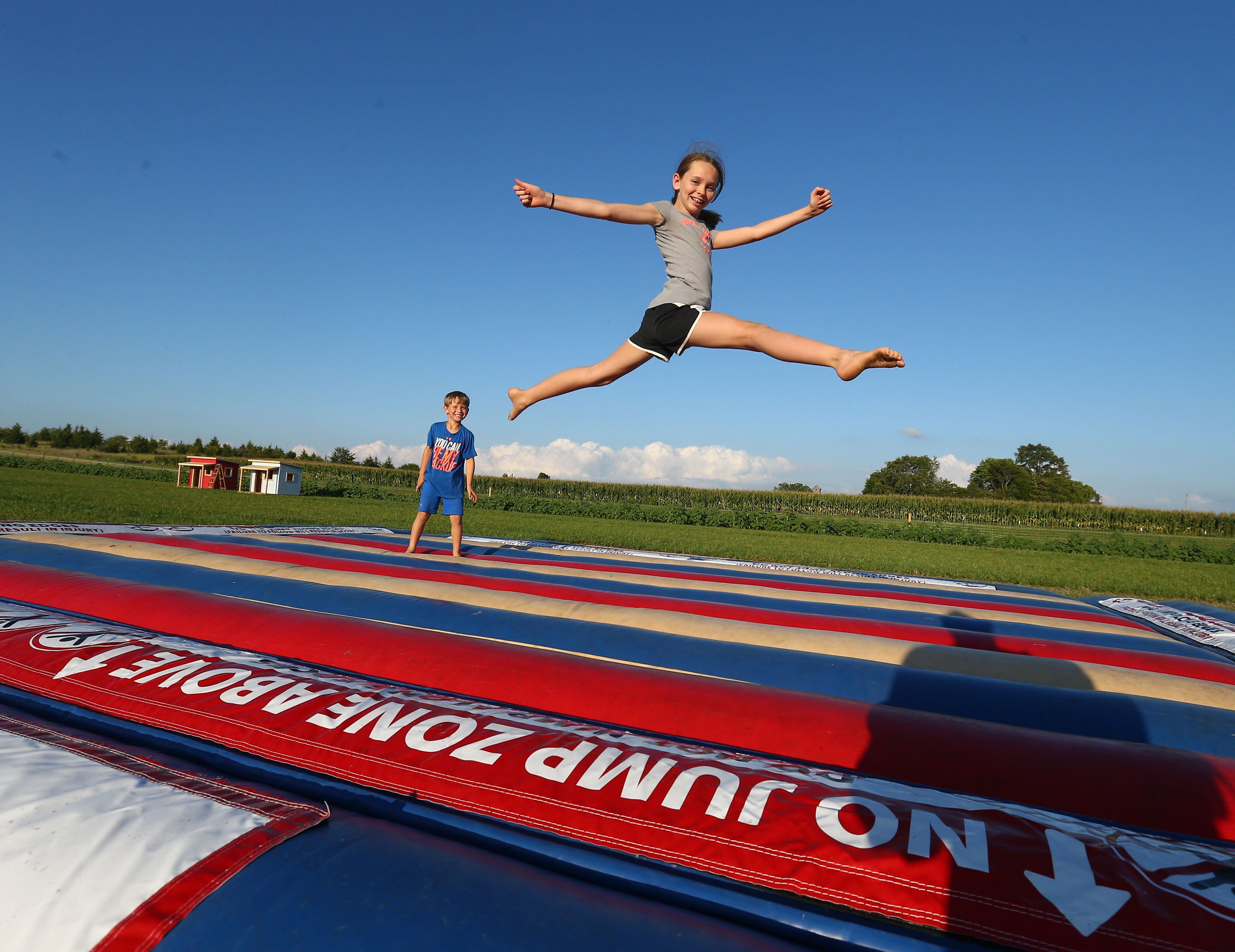 Megan Kane 11, leaps in the air on a giant inflatable jump pad as her brother Alex 5, watches behind at Kane Family Farms pumpkin patch on Tuesday Sept. 6, 2022 in Ottawa.